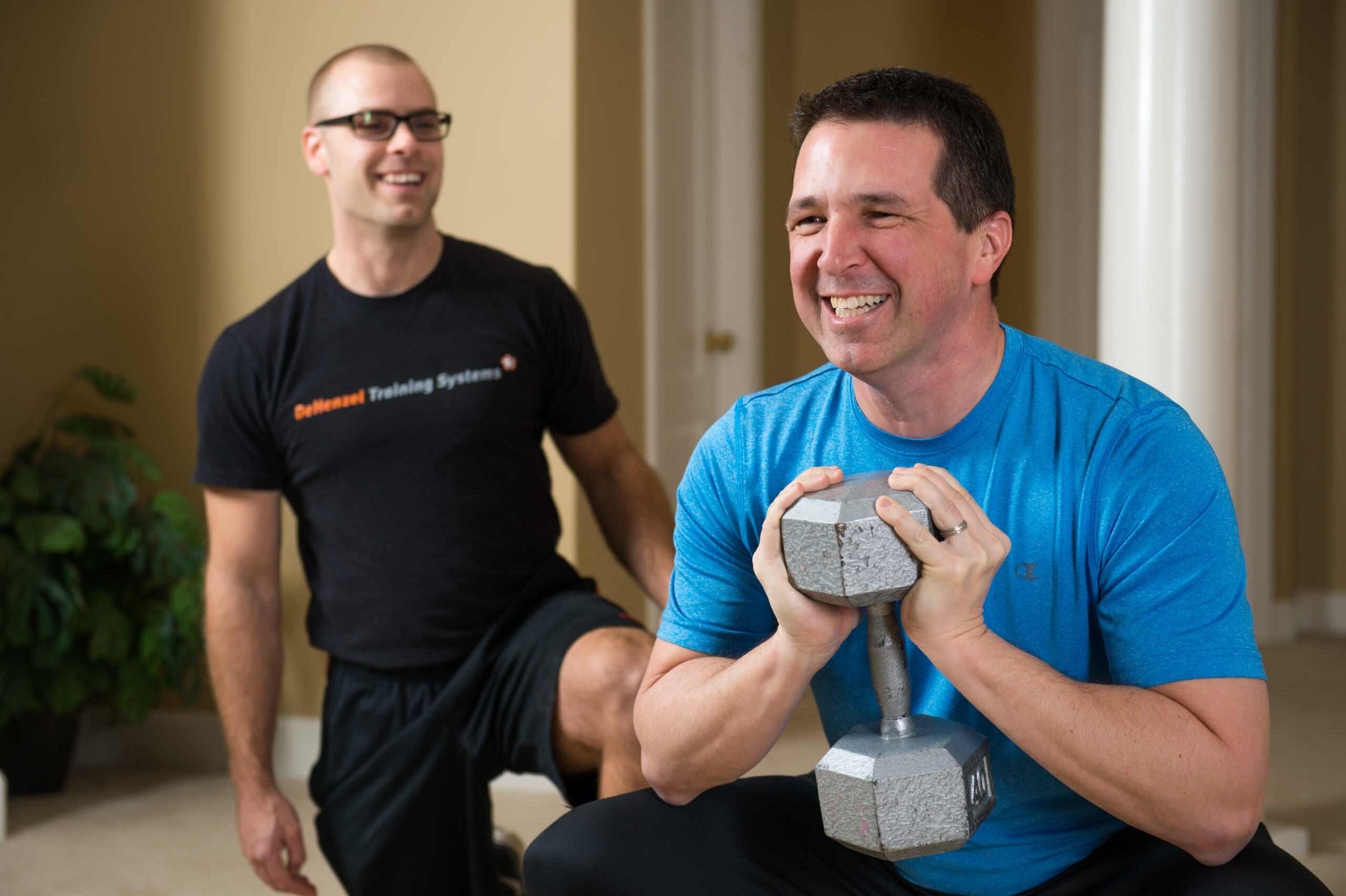 Man completing dumbbell squat with trainer