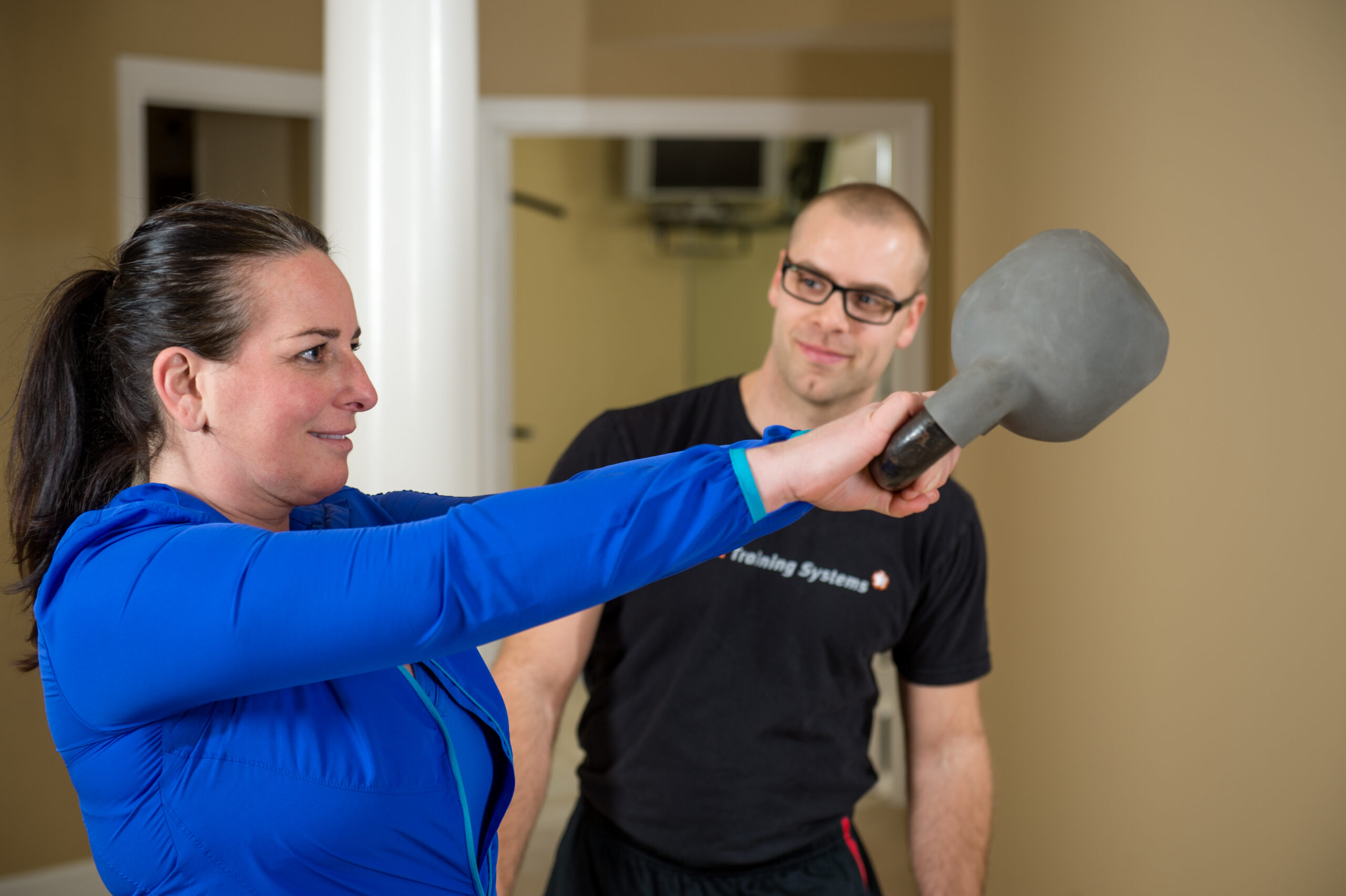 Woman completing kettlebell swings with trainer