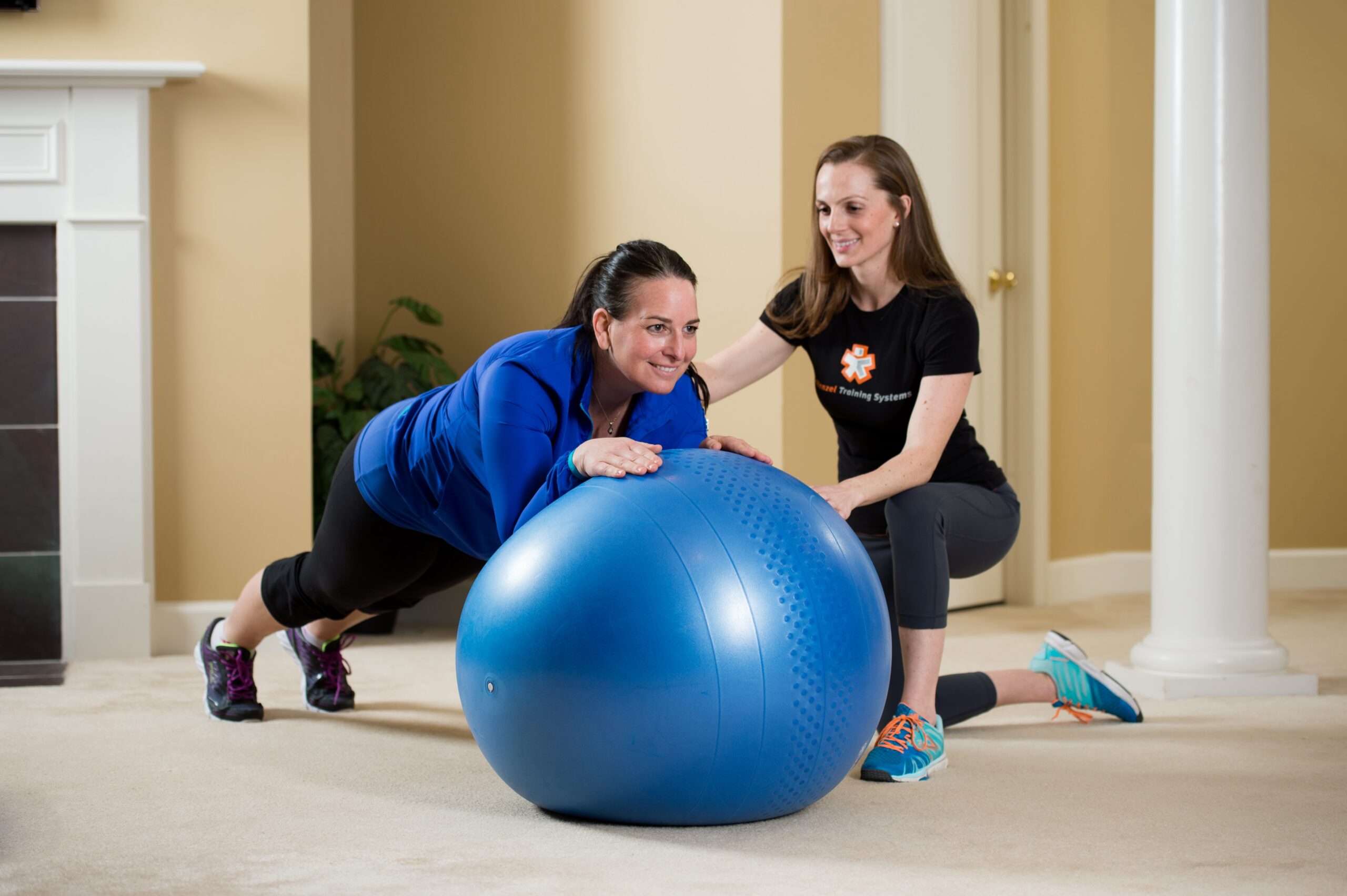Woman uses an exercise ball as her in home personal trainer supports her